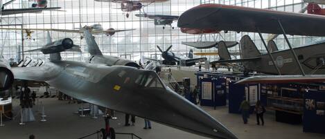 A museum with various aircraft on display, including a prominent silver fighter jet.