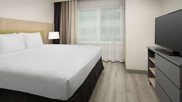 Une chambre d’hôtel avec un grand lit, une télévision, une lampe et une fenêtre avec des rideaux.