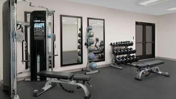 Un gimnasio con equipo de levantamiento de pesas, espejos y mancuernas.