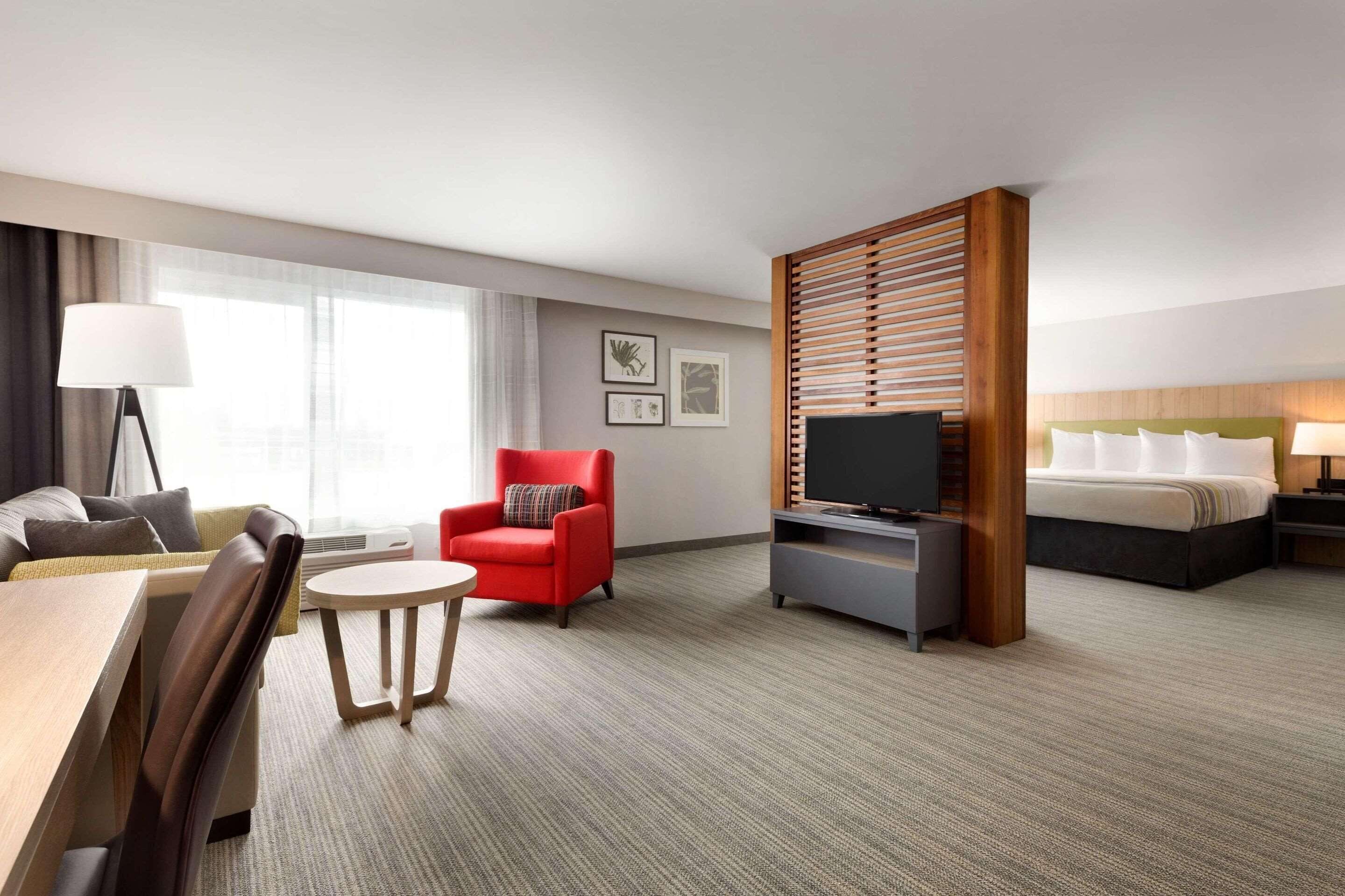 A hotel room with a bed, a TV, a desk, a chair, and a sofa.
