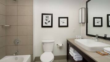 Un baño moderno con bañera, inodoro y tocador con espejo.