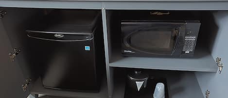 A kitchenette with a refrigerator, microwave, and coffee maker.