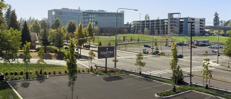 A parking lot with a Country Inn & Suites sign, surrounded by greenery and modern buildings.