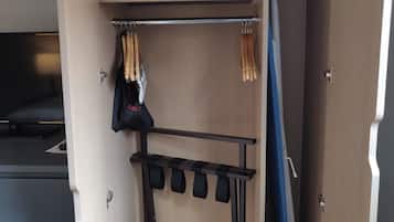 Un armario compacto con un colchón encima, una percha para ropa y un zapatero.