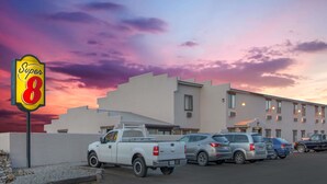 Un motel Super 8 con estacionamiento y un edificio de múltiples ventanas y techo plano.
