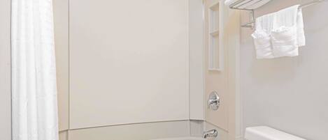 A bathroom with a bathtub, a toilet, and a towel rack with towels.