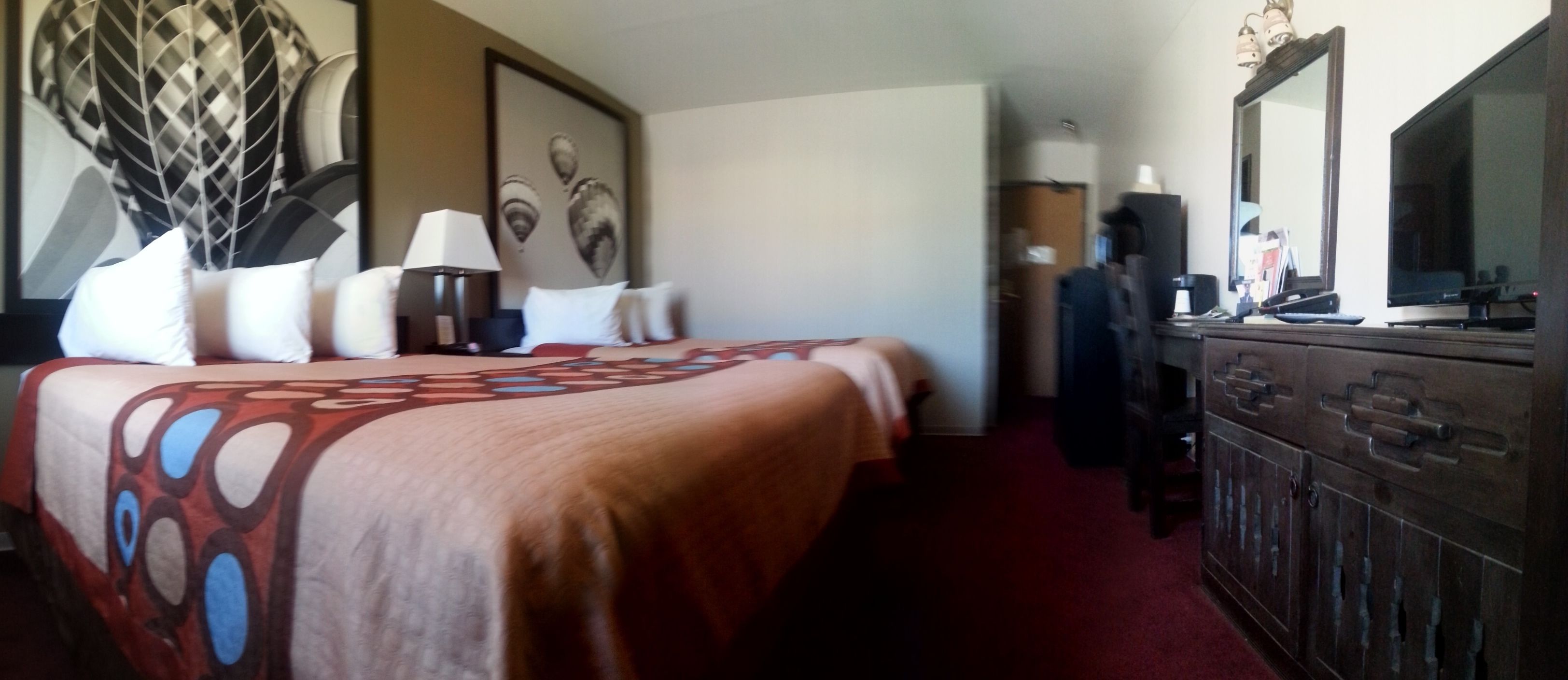 Habitación de hotel con una cama grande, cómoda, un espejo y un televisor.