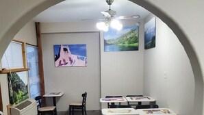 Un comedor con mesas y sillas, un ventilador de techo y obras de arte en las paredes.