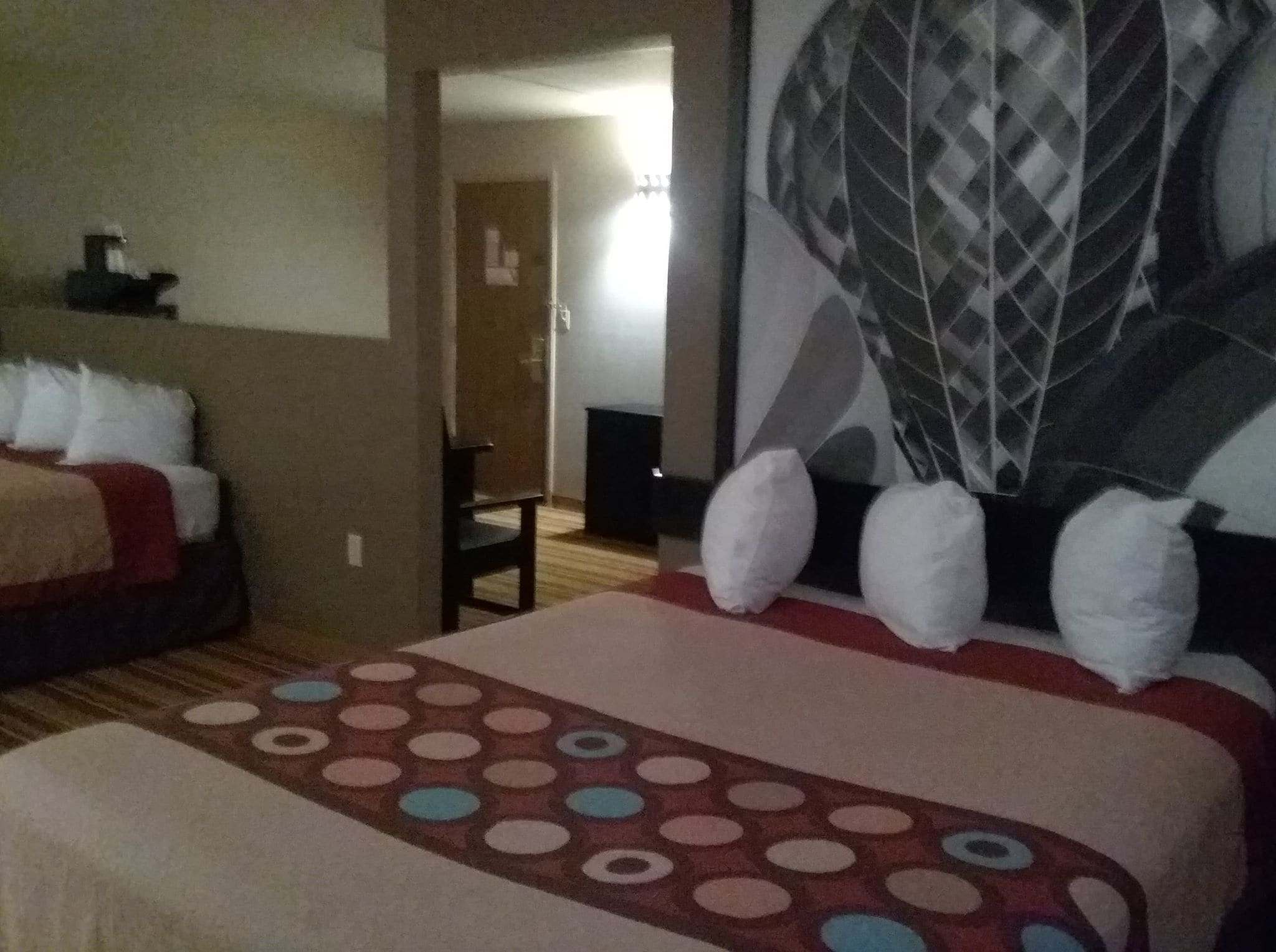 A hotel room with a bed, a chair, and a large wall mural.
