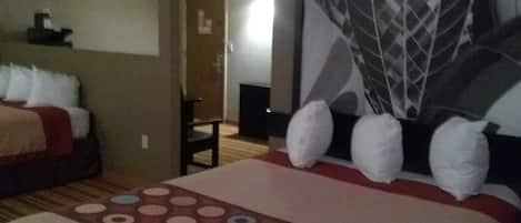 A hotel room with a bed, a chair, and a large wall mural.