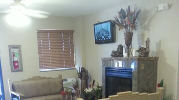 Una sala de estar con un sofá, una mesa de centro, una chimenea y un televisor montado en la pared.