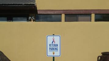Señal de estacionamiento para veteranos con símbolo de lazo rojo.