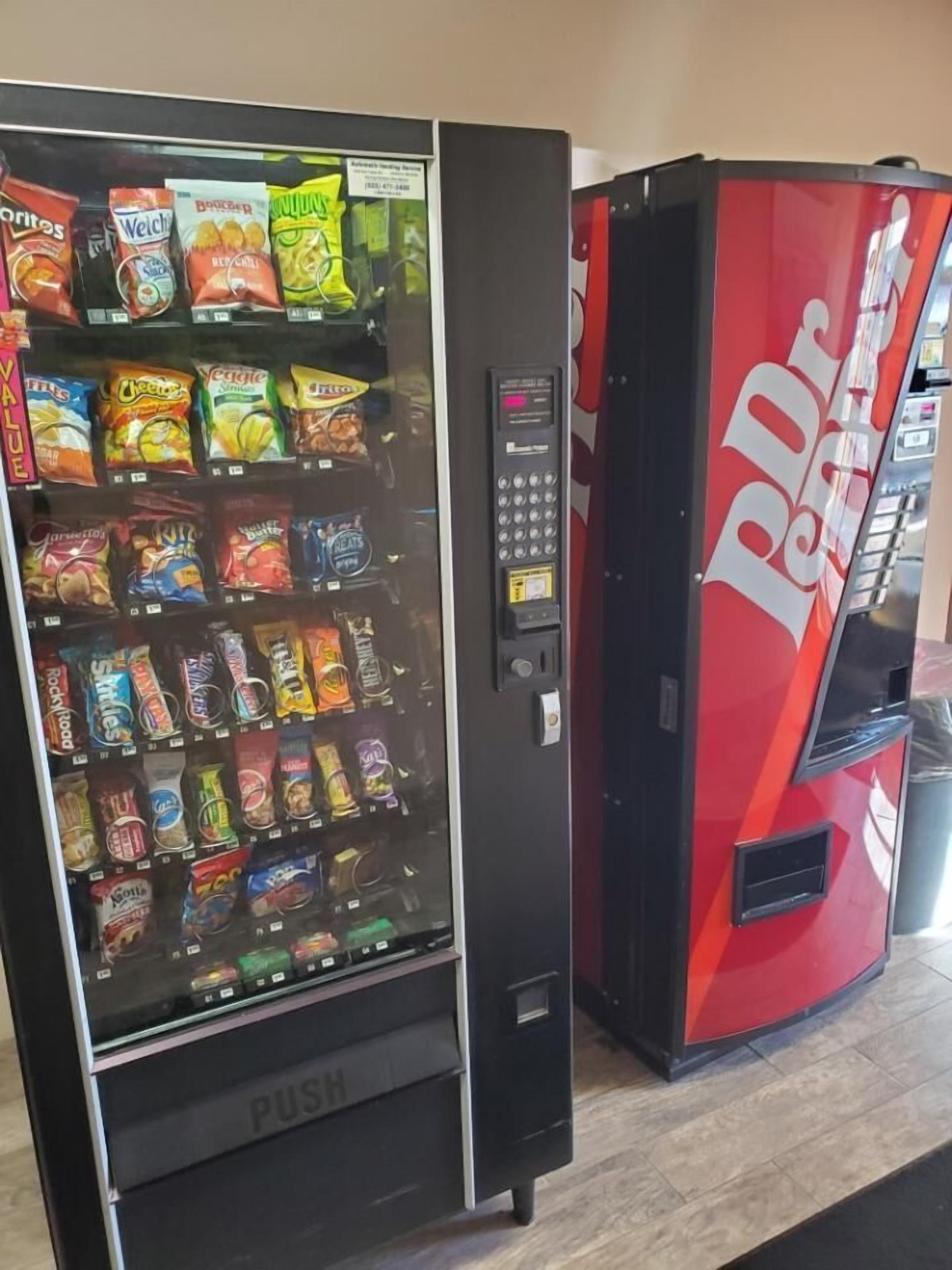 Een automaat met diverse snacks en een rode machine met de tekst 'Dr Pepper'.