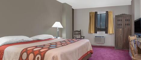 Una habitación de hotel con una cama grande, un escritorio, una silla, un armario y una ventana con cortinas.