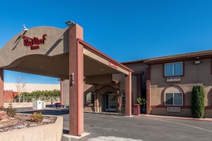 Un Red Roof Inn con entrada cubierta, estacionamiento y fachada color beige.