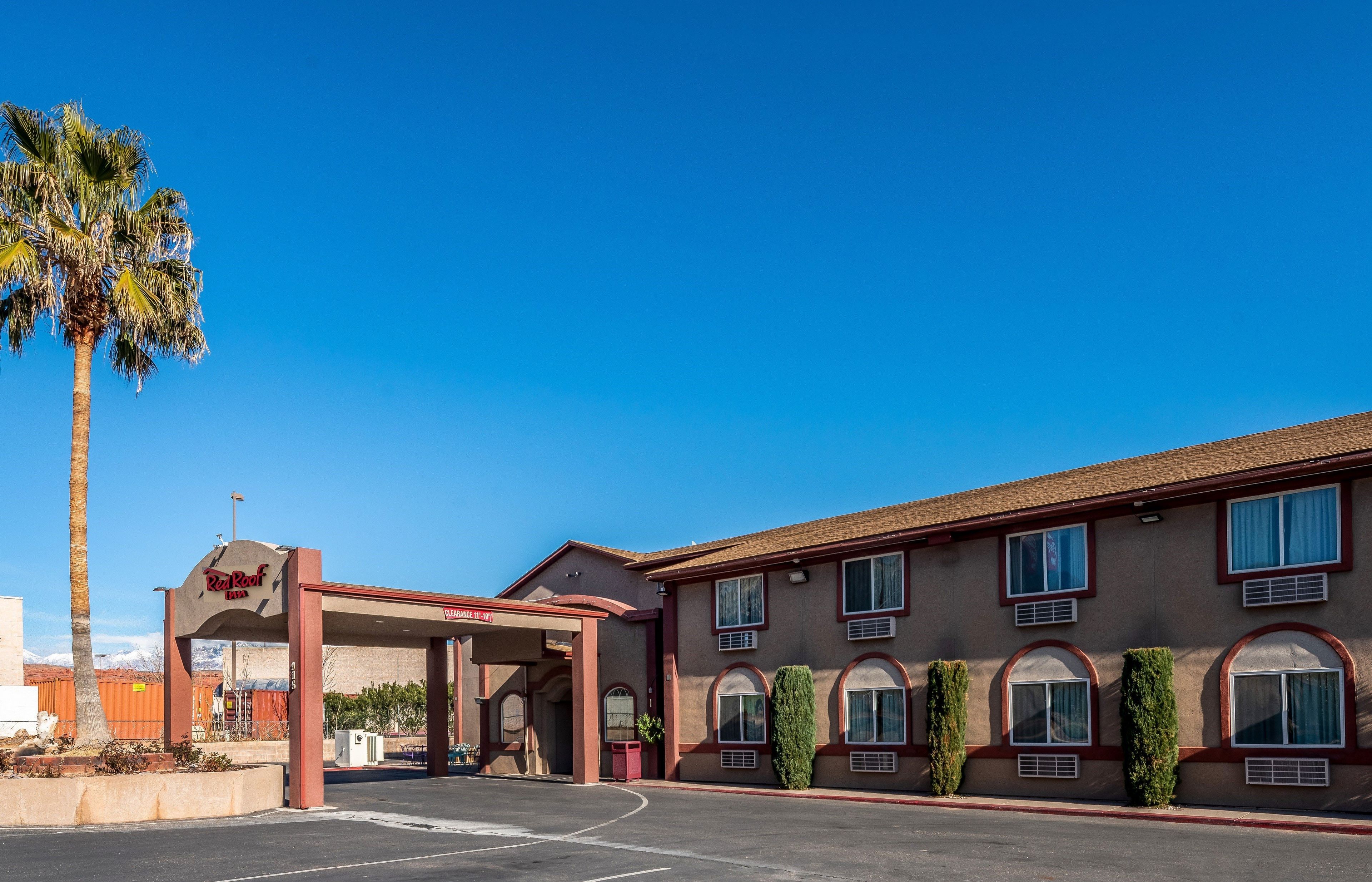 Ein Red Roof Inn mit blauem Himmel, Palmen und einem Parkplatz.