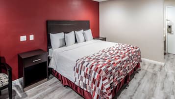 Una habitación de hotel con una cama, una mesita de noche, un cajón y una silla.