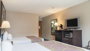 Quarto de hotel com duas camas, televisão, micro-ondas e uma mesa com abajur.