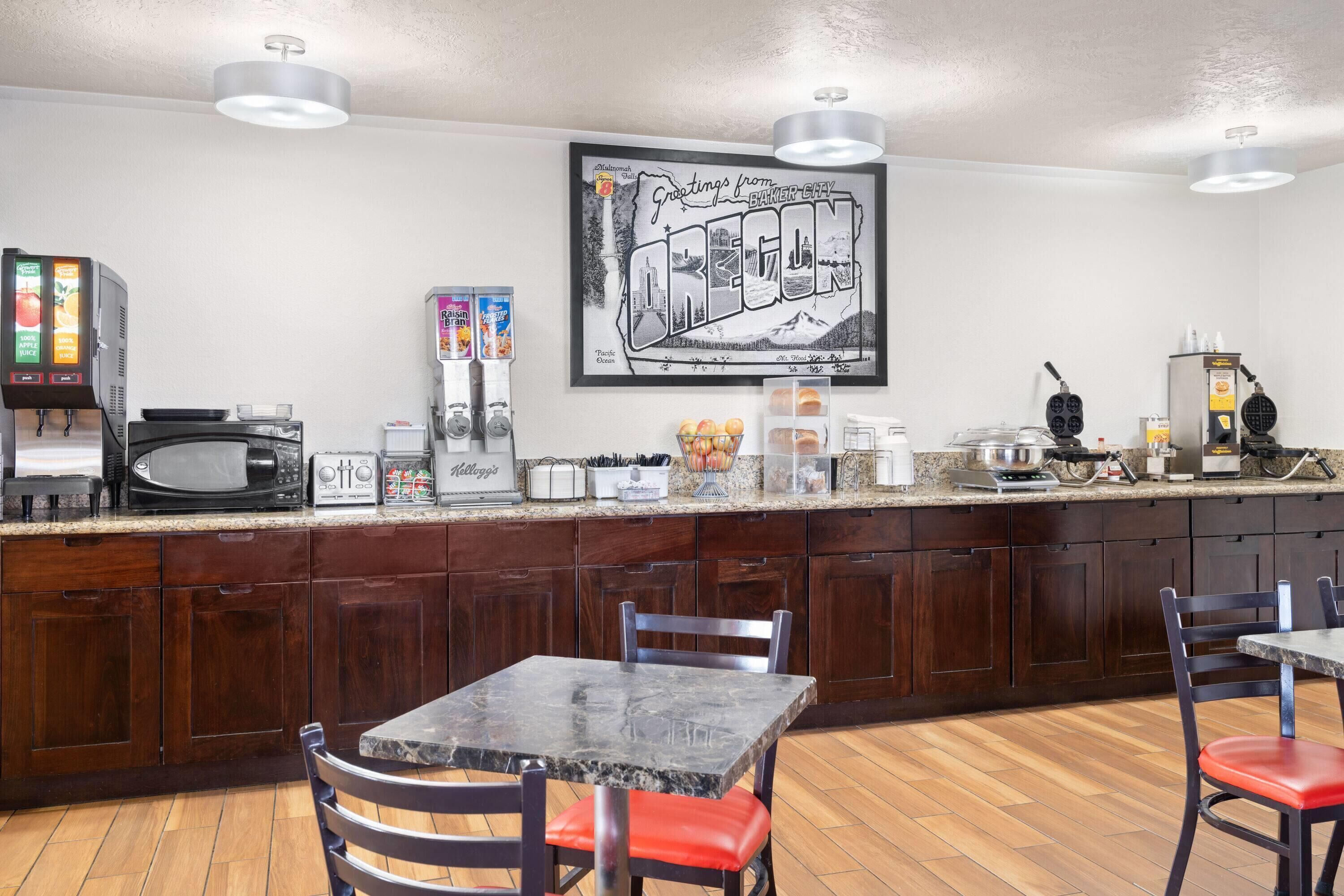 A kitchen with a microwave, toaster, and coffee maker. There is a framed picture on the wall and a counter with various items.