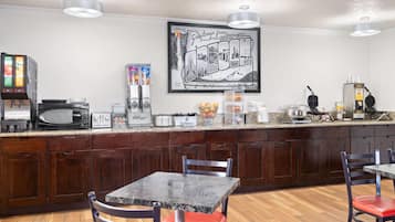 A kitchen with a microwave, toaster, and coffee maker. There is a framed picture on the wall and a counter with various items.