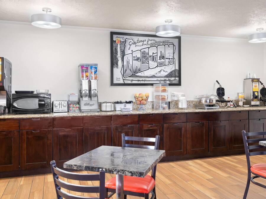 A kitchen with a microwave, toaster, and coffee maker. There is a framed picture on the wall and a counter with various items.