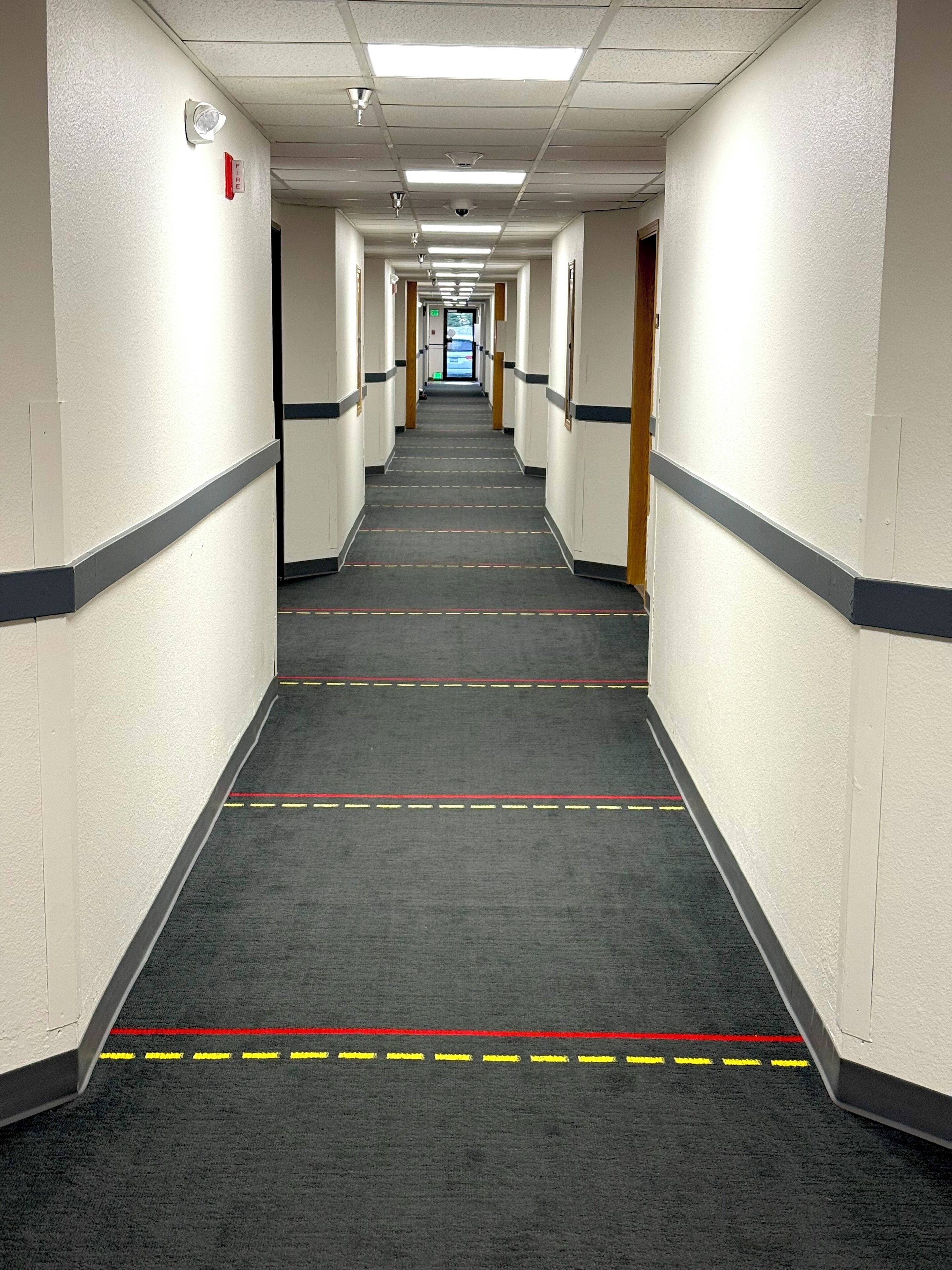A long, narrow hallway with carpeted floors and white walls.