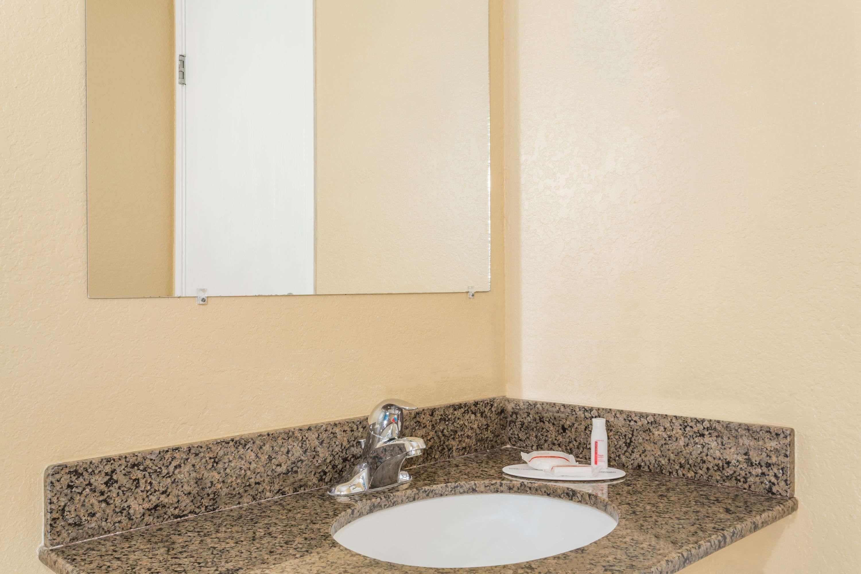 A bathroom with a granite countertop, a white sink, and a mirror above it.