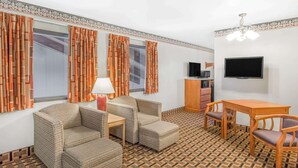 Una habitación con un sofá, dos sillones, una mesita, un televisor y un suelo estampado.