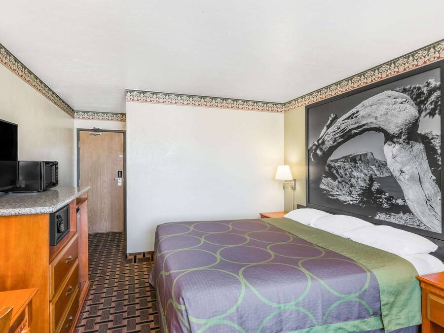 A hotel room with a bed, a TV, a desk, and a door.