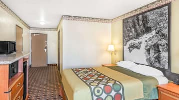 A hotel room with a bed, a desk, a television, and a painting on the wall.