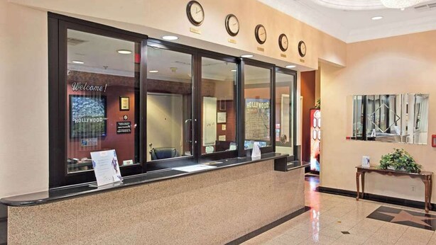 A reception desk with a 'Welcome!' sign, a clock, and a 'Hollywood' sign in the background.