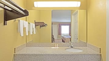 Een badkamer met een granieten aanrecht, een wastafel, een spiegel en een handdoekrek met meerdere handdoeken.