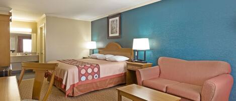 A hotel room with a bed, a sofa, a desk, and a chair.