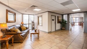 A spacious lobby with a leather sofa, wooden coffee table, and a potted plant. - Port Allen Inn (Port Allen)