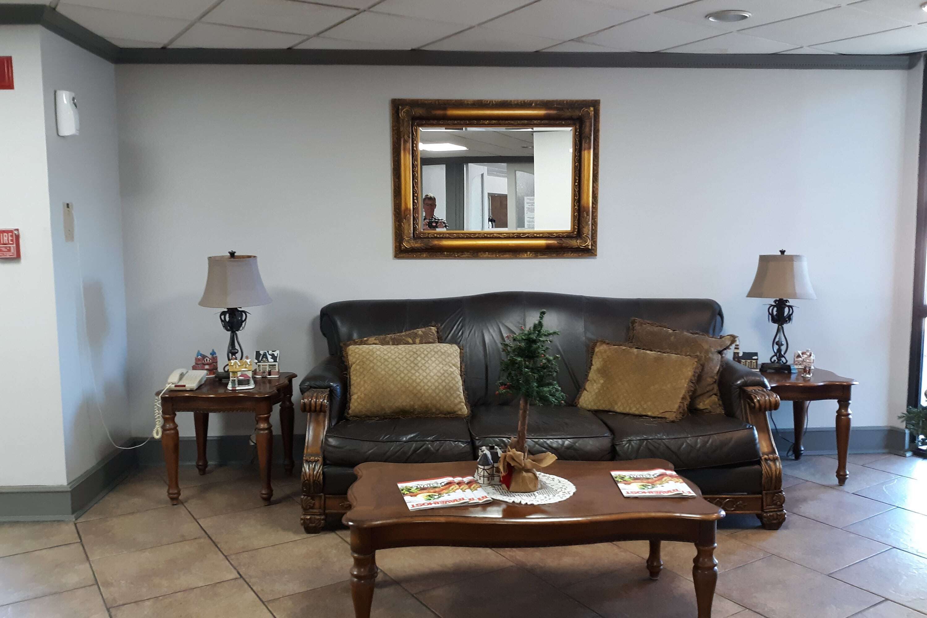 A living room with a leather sofa, two side tables, a coffee table, and a mirror on the wall.