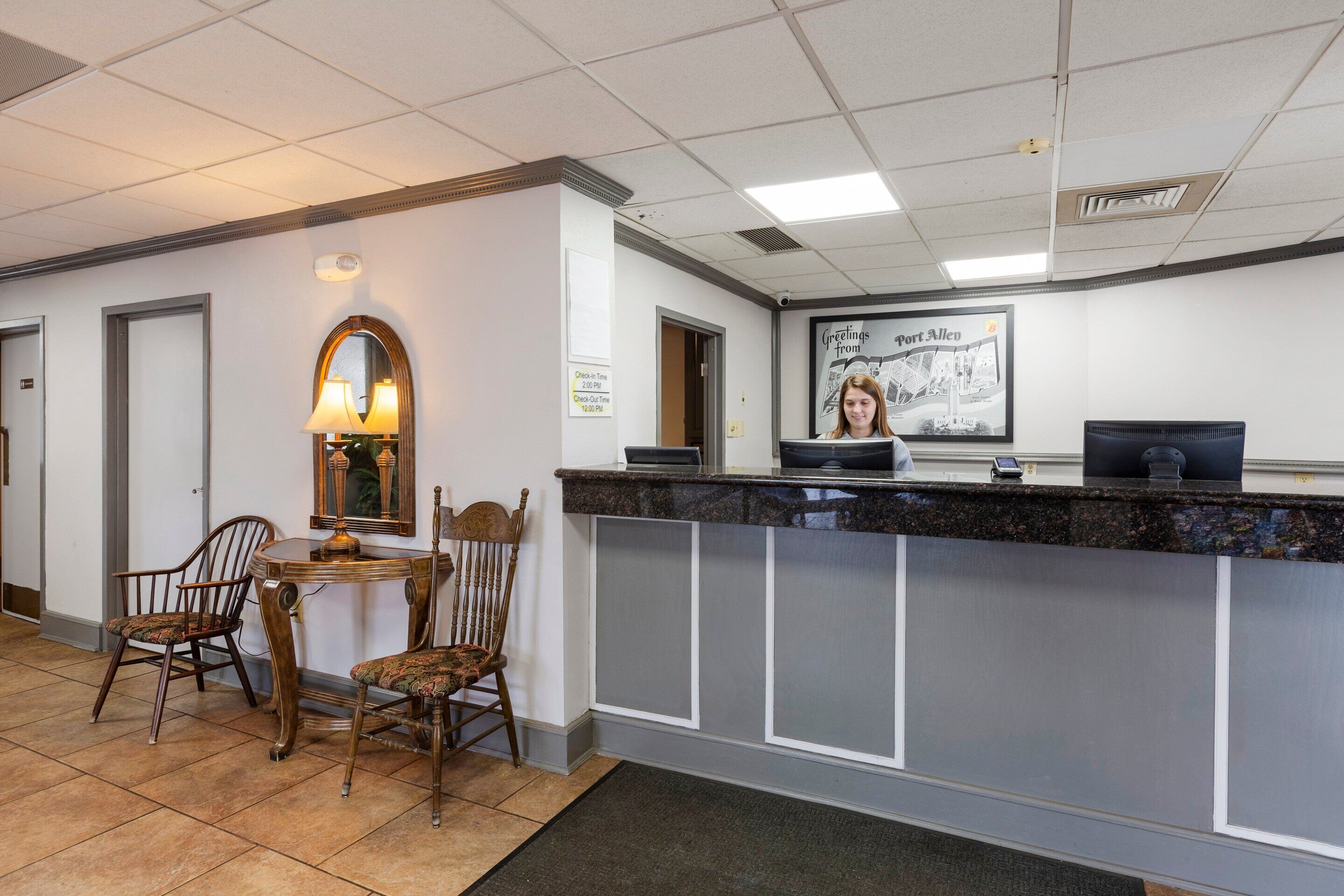 A reception area with a desk, chairs, a mirror, and a framed welcome sign.