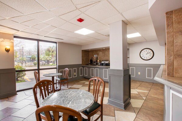 A restaurant with a marble table, wooden chairs, a kitchen area, and a clock on the wall. - Port Allen Inn (Port Allen)