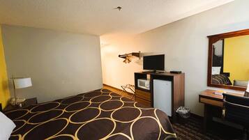 A hotel room with a large bed, a desk with a computer, a television, a mirror, and a microwave.