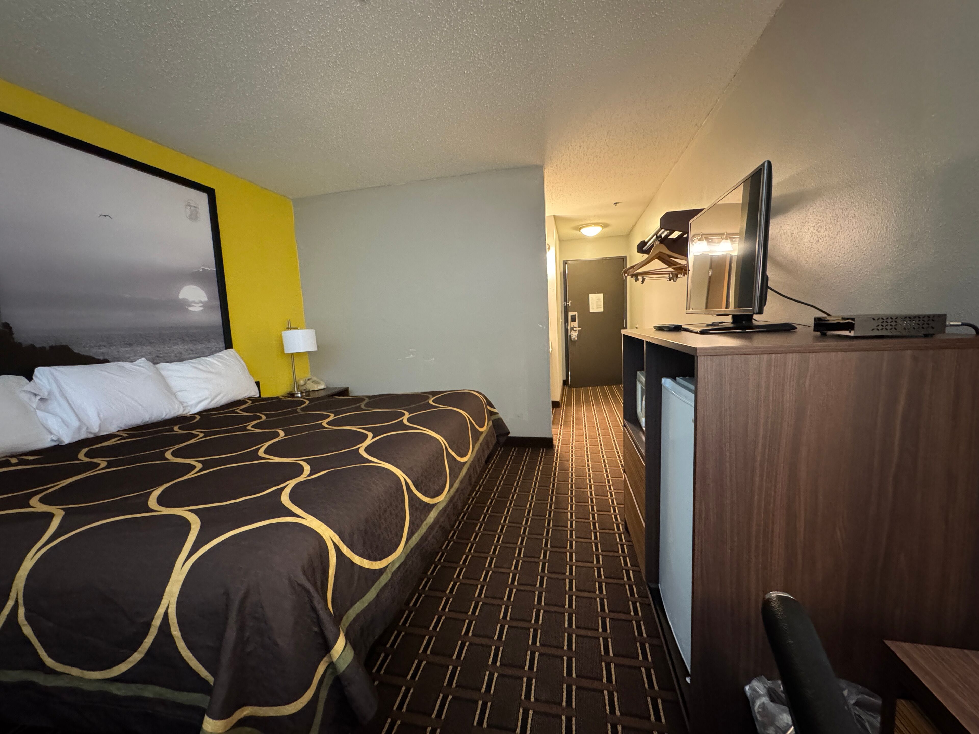 Une chambre d’hôtel avec un lit, un bureau avec une télévision et une vue sur la ville.