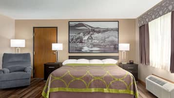 A hotel room with a bed, two bedside tables, a chair, a large window with curtains, and a wall-mounted picture.