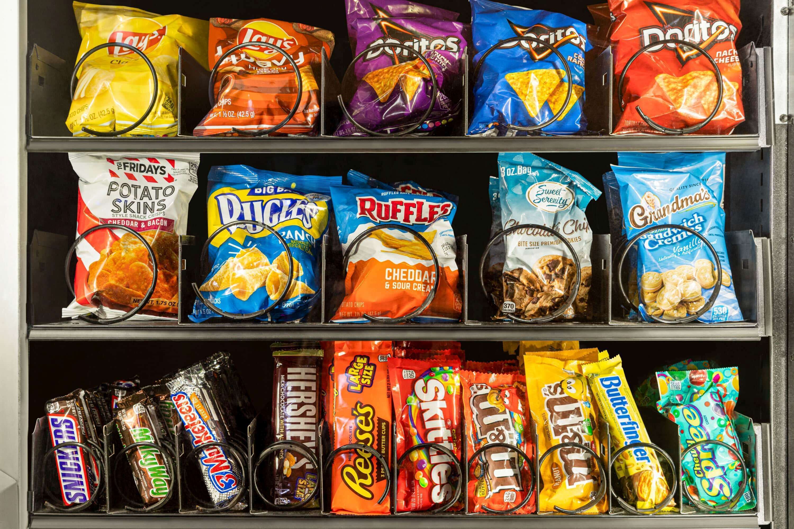 Una máquina expendedora de refrigerios con varias opciones de papas fritas y dulces.