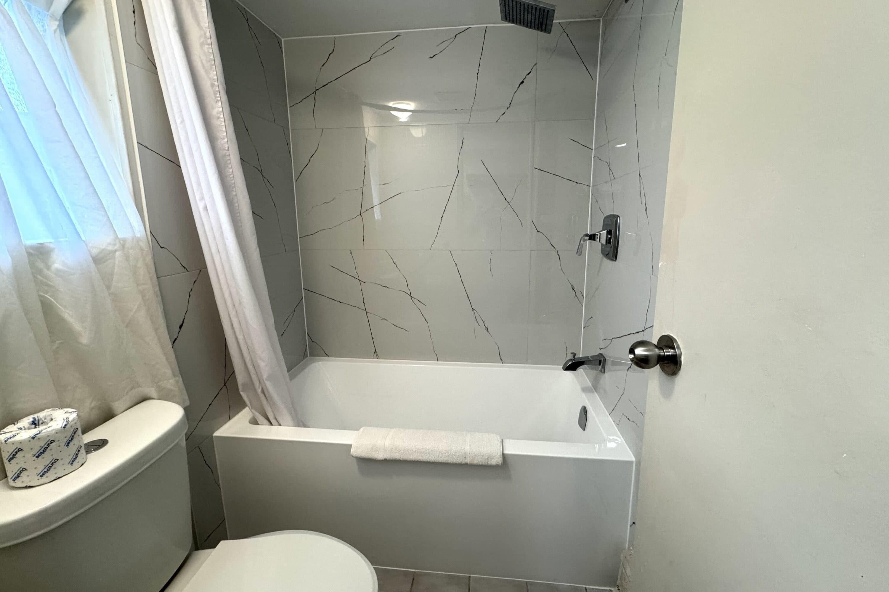 Baño con bañera, inodoro y cortina de ducha.