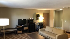 A hotel room with a television, microwave, refrigerator, sofa, and a small desk with a lamp. - Super 8 by Wyndham S Jordan/Sandy/Slc Area (South Jordan)