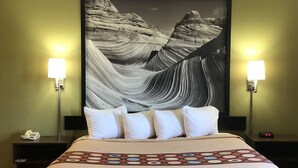 A hotel room with a large bed, two bedside lamps, a nightstand with a phone, and a framed artwork on the wall. - Super 8 by Wyndham S Jordan/Sandy/Slc Area (South Jordan)