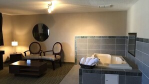 Et hotelværelse med siddeområde, stort spejl, badekar og et lille bord.