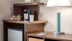 Et hotelværelse med minibar, kaffemaskine, lampe og lille køleskab.