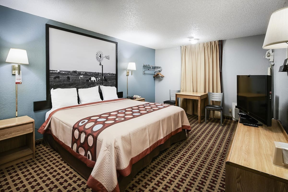 Une chambre d’hôtel comprenant un lit, des tables de chevet, un bureau, une chaise, un téléviseur et une horloge fixée au mur.