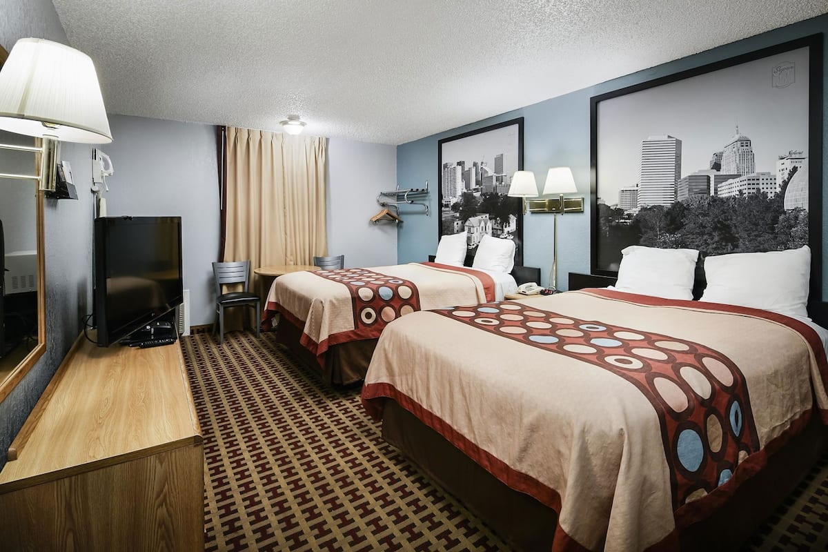 Une chambre d’hôtel avec deux lits, une télévision, un bureau et une vue sur la ville.