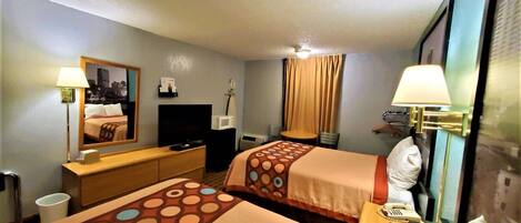 A hotel room with two beds, a desk, a chair, a TV, a lamp, and a phone.