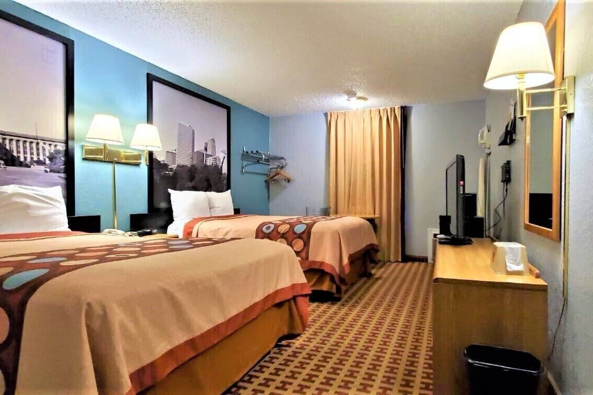 Une chambre d’hôtel avec deux lits, un bureau, un miroir et un téléviseur fixé au mur.